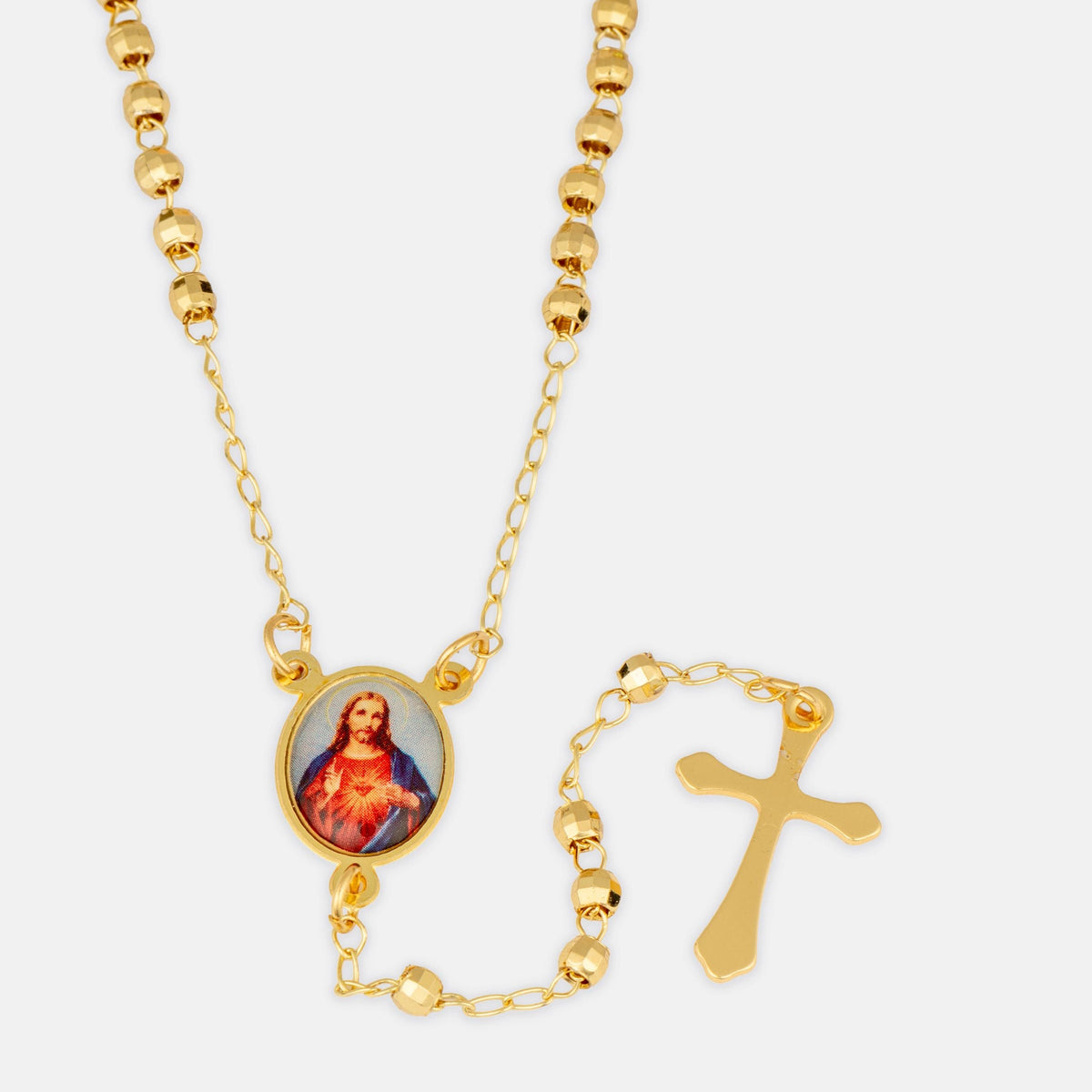 Gold beaded rosary necklace with a Sacred Heart of Jesus oval medallion and a separate gold cross pendant, shown on a light gray background.