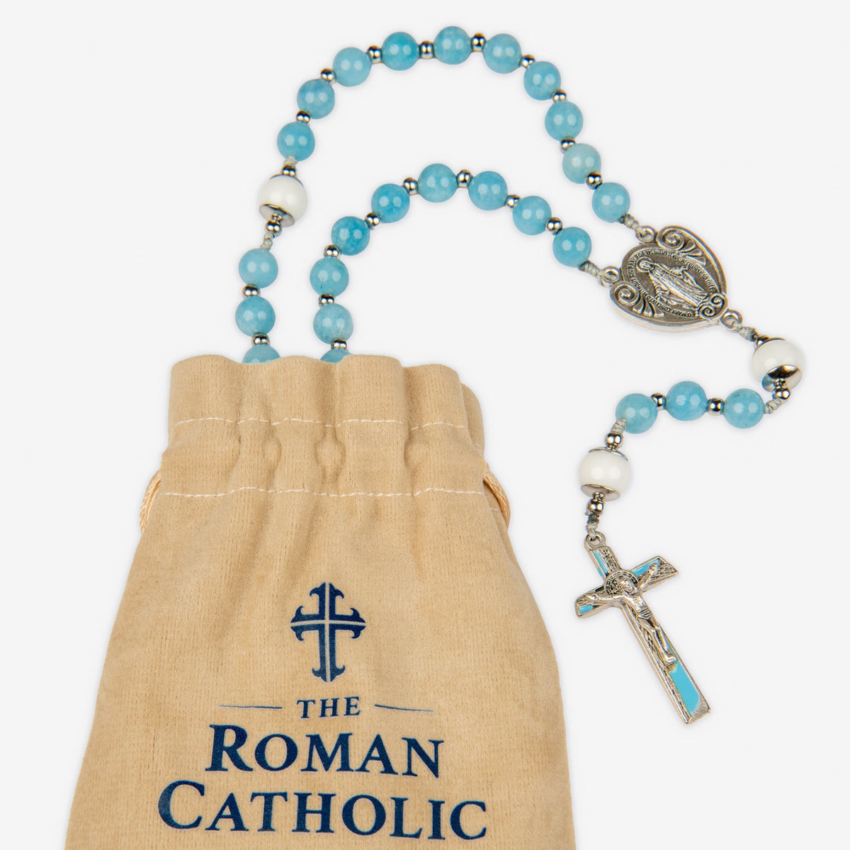 A light blue and white beaded rosary with silver-tone metal details, displayed next to a beige drawstring pouch printed with 'THE ROMAN CATHOLIC STORE' in navy blue.