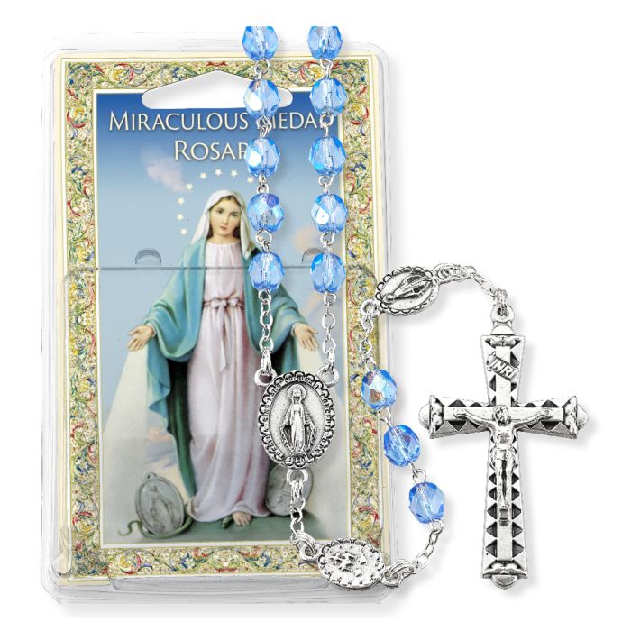 Miraculous Medal Rosary with blue beads on a colorful packaging background
