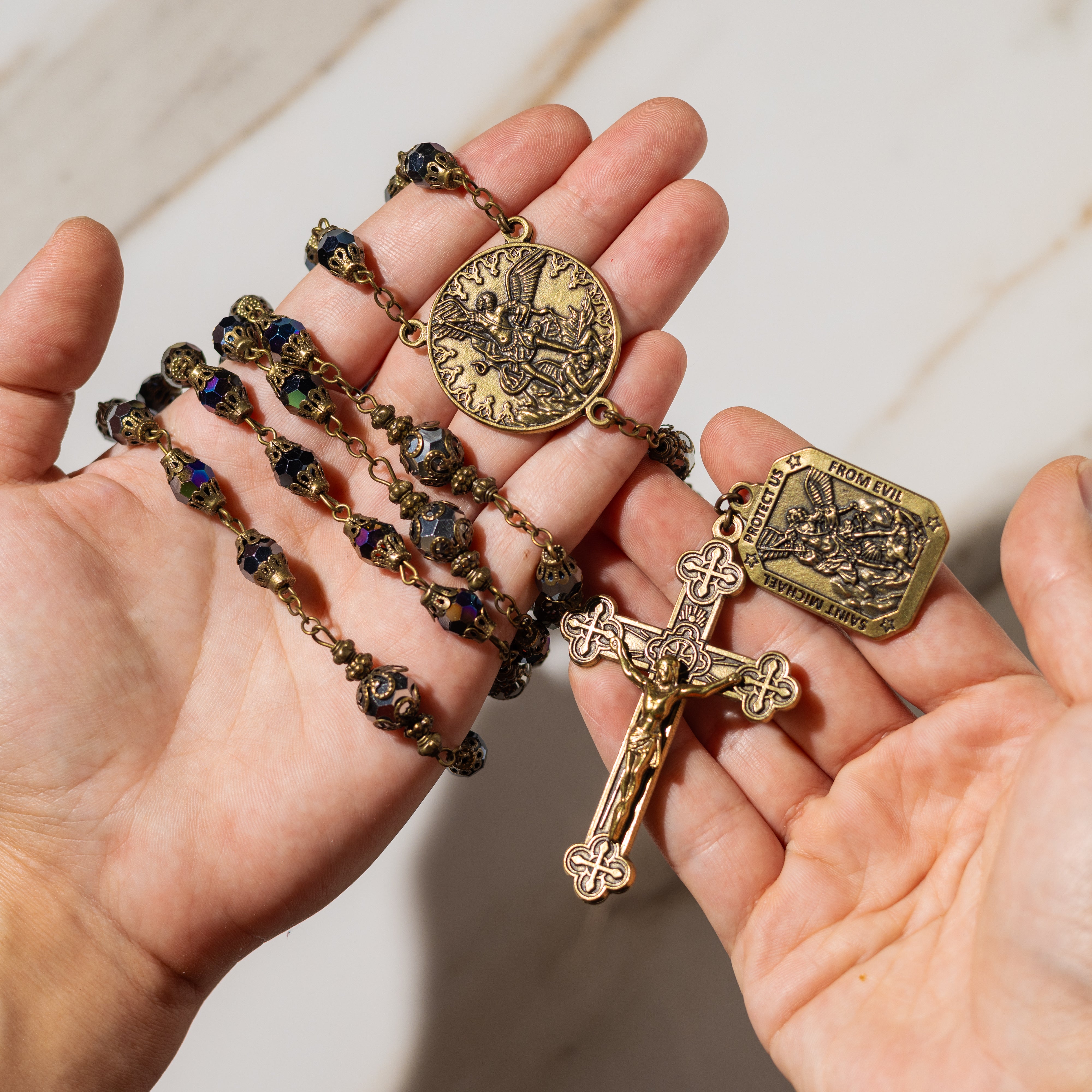 Vintage bronze rosary with ornate beads and crucifix, featuring protective Saint Michael medal.
