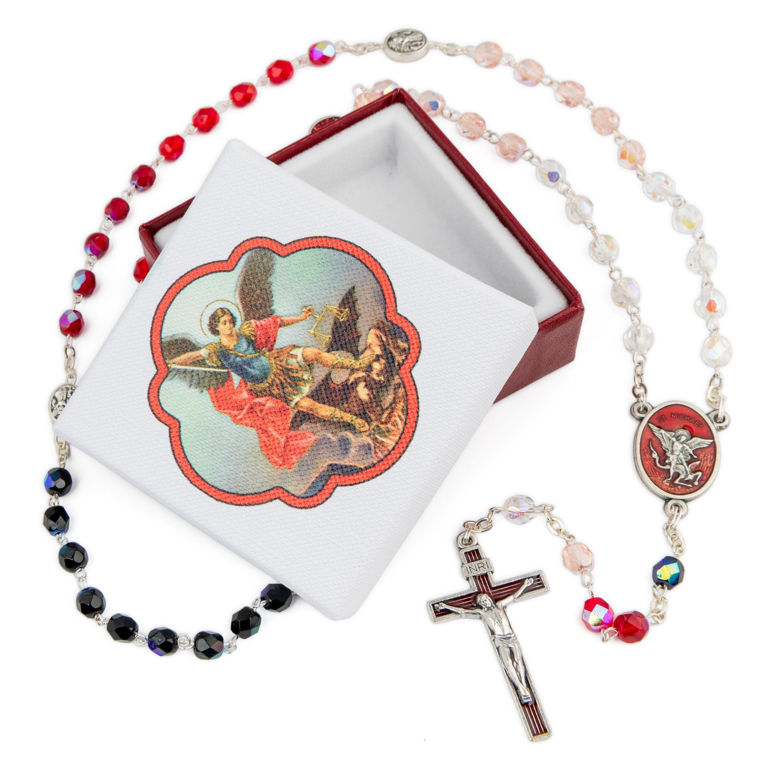 A religious rosary necklace with a silver-tone crucifix, red and multicolor beads, shown next to its white presentation box with a red interior and an illustration of the Virgin Mary and baby Jesus.